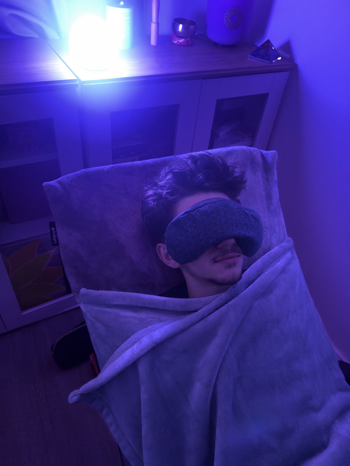 Client enveloppé dans un plaid, bandeau lesté sur les yeux, ambiance lumineuse tamisée